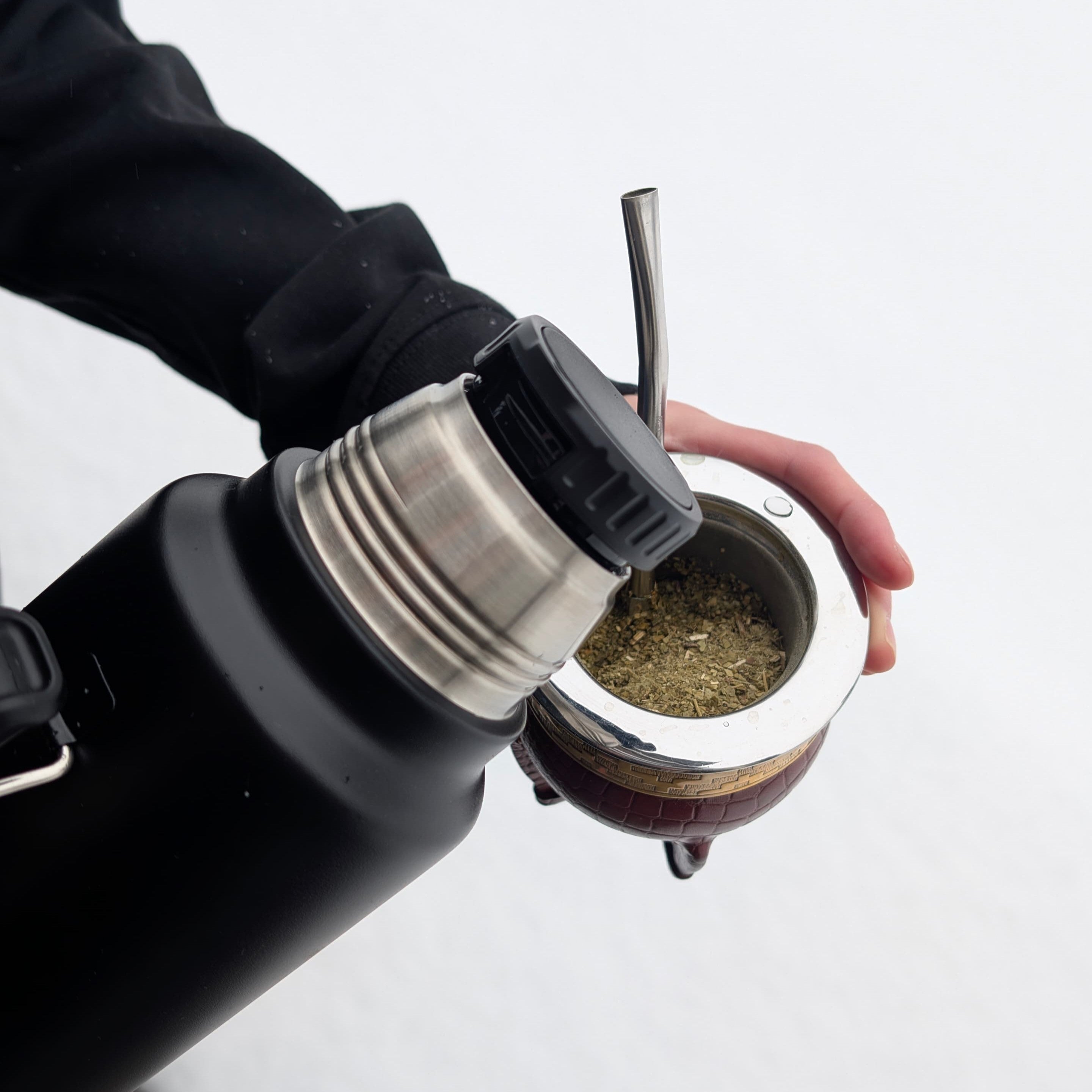 Pouring yerba mate into a gourd with yerba mate and a bombilla