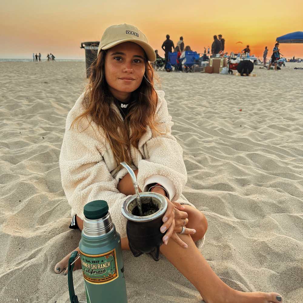 A woman handing a yerba mate gourd to a friend