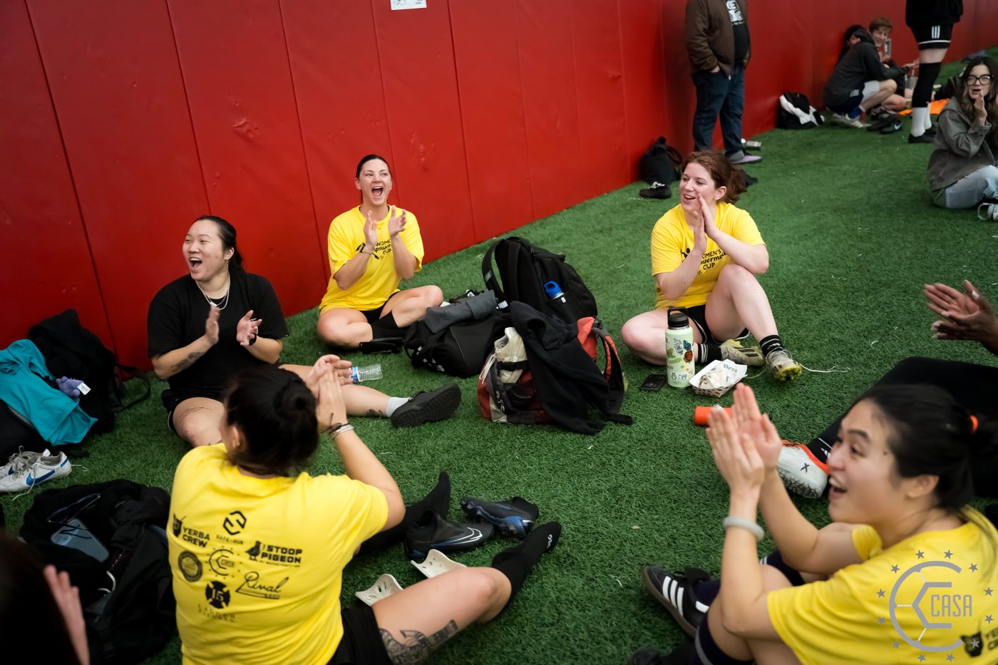 Women players sitting and laughing together on the turf.