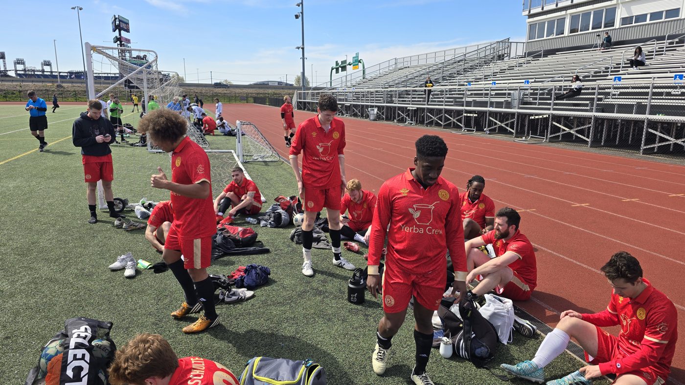 Yerba Crew soccer team members gather and rest on a stadium track after a match.