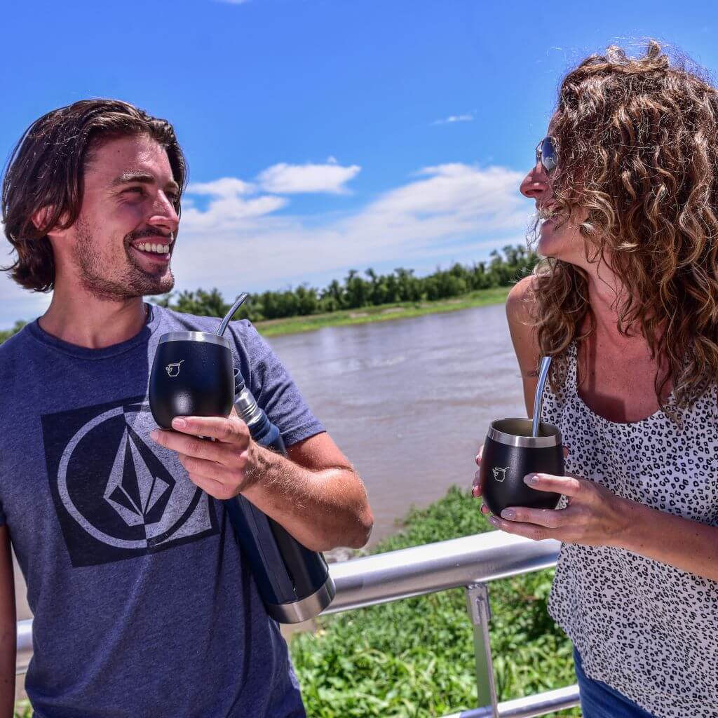 Two people drinking yerba mate out of a stainless steel gourd