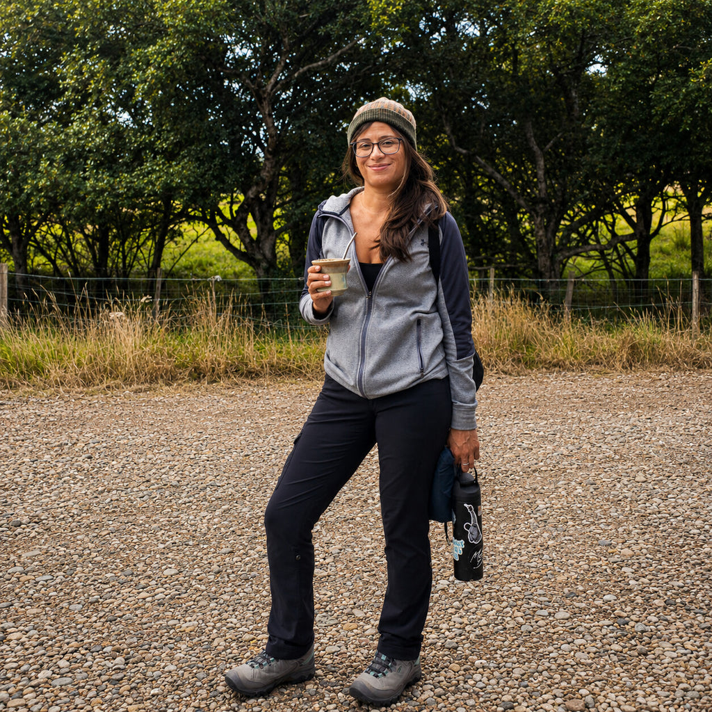 A woman drinking yerba mate from the Iruya ceramic gourd while walking on a gravel path in the countryside.